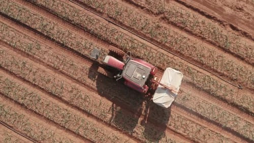 Pesticide Sprayer Tractor working on a large field, Aerial follow footage
