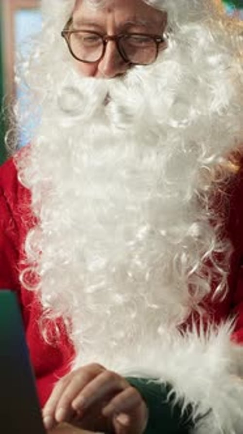 Vertical Video Santa Claus in His Red Suit Browses Webpages in His North Pole Workshop