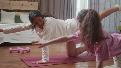 Woman and Girl Do Yoga at Home Together