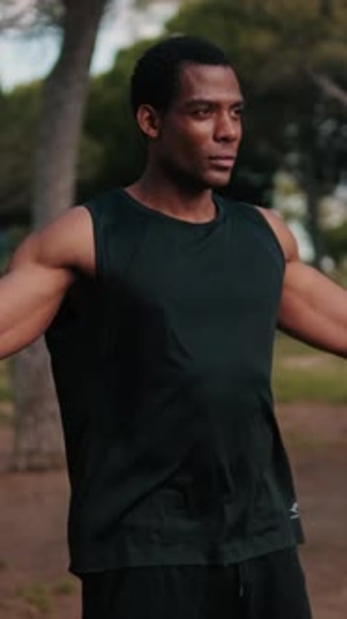 Vertical video, Muscular Man Stretching in Park for Fitness Workout