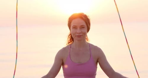 Fit woman jumping rope at the beach during summer vacation. Slow motion