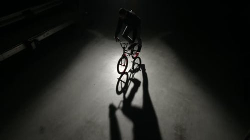 Young bmx rider performing extreme tricks in an industrial dark warehouse