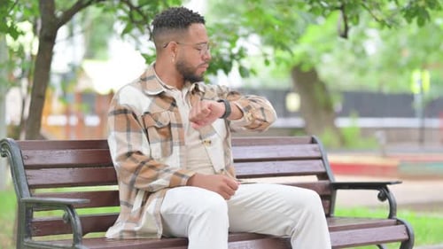 Waiting Hispanic Man Checking Wrist Watch on Park Bench