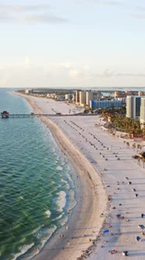 White sandy shoreline with ocean waves and beachfront hotels — aerial perspective