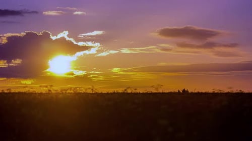 Golden sunrise cloudscape over a farmland field - time lapse