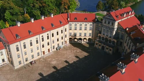 Birds fly over Nesvizh Palace in the morning. Cinematic drone shot of a castle and park. Aerial view