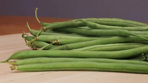 Ein Stapel frischer grüner Bohnen, eine Grundnahrungszutat, liegt auf einem Holzschneidebrett. Diese natürlichen