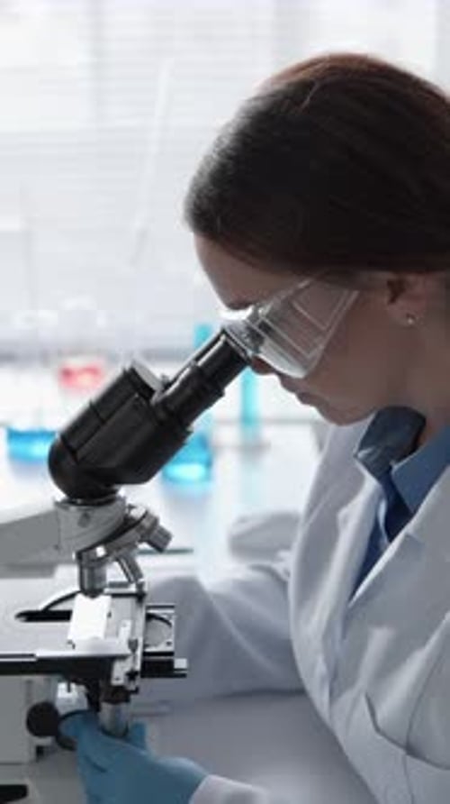 Young Scientist Working With Microscope and Computer