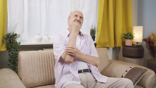 Senior Man Rubbing Sore Wrist on Couch