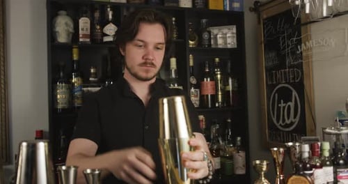Bartender Mixing Cocktail with Golden Shaker in Bar