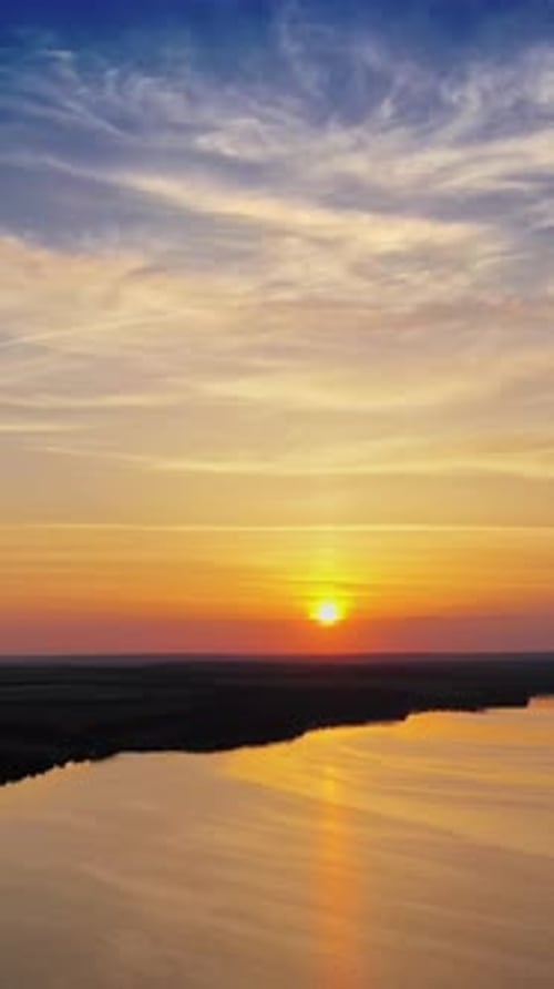 Toller orangefarbener Sonnenuntergang über dem Fluss. Magische Luftaufnahme der Abendsonne zwischen Wolken.