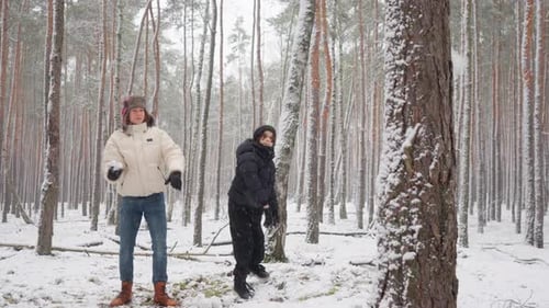Brothers furiously throwing snowballs at a tree, releasing pent-up emotions