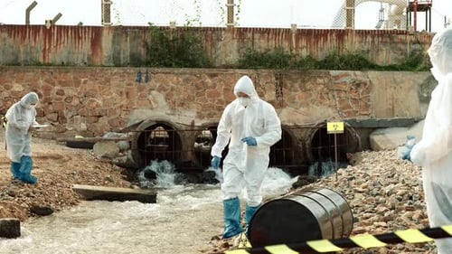 Figures Sampling Water Near Industrial Plant