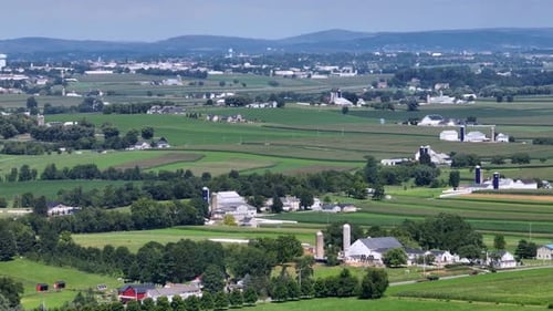 Rural American Landscape with farm houses and green agricultural fields n summer. Driving cars and t