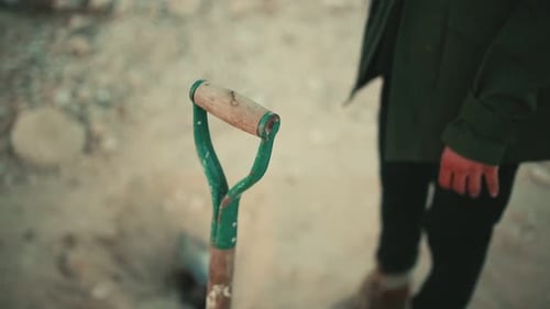 Close up of man taking a shovel to dig in a hostile and arid environment