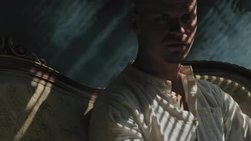 Man Sits on Couch in Shadows