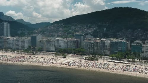 Inclinação aérea para baixo fotografou turista na lotada praia de Copacabana, no Rio de Janeiro, com paisagem urbana