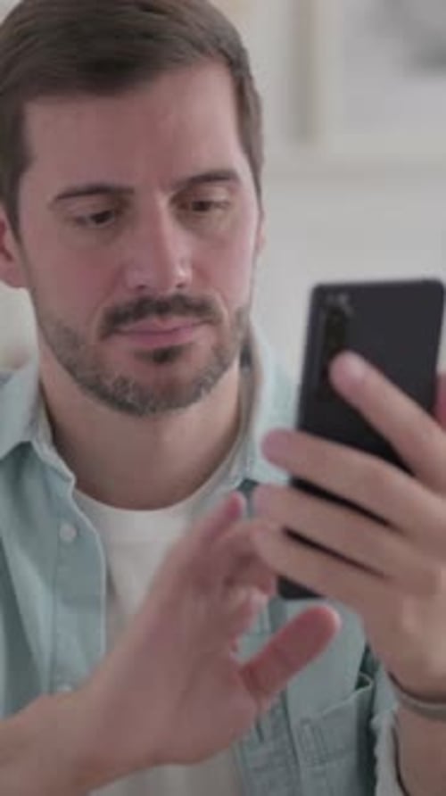 Young Man Browsing Internet on Smartphone, Vertical Video