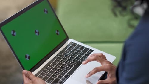 A black woman with a laptop. Working with the touchpad. Green screen. Close-up.