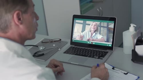 Old Male Doctor Talking To Senior Female Patient By Tele Medicine Online Video Call In Clinic. Ph...