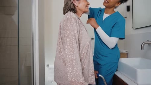 Young Woman Brushing Senior Woman's Hair in Bathroom