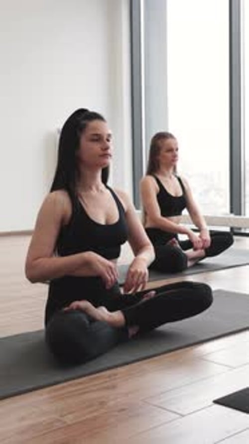 Two Young Women Meditating in Bright Room