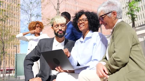 Diverse Group Discusses Laptop in Urban Setting