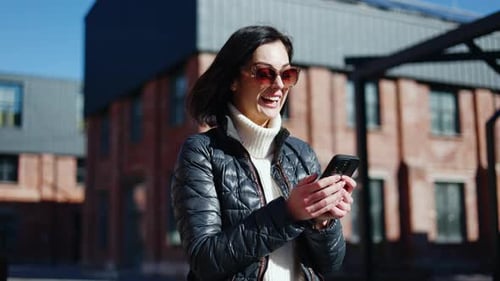 Woman Looks at Phone and Celebrates Outside