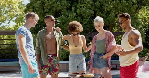 Happy diverse group of friends having bbq at pool in summer