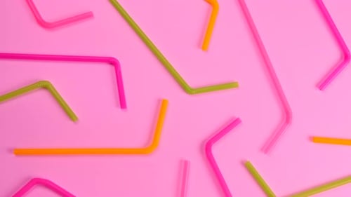 Rotating Multicolored Cocktail Straws on a Pink Background Top View the Concept of Celebrating a