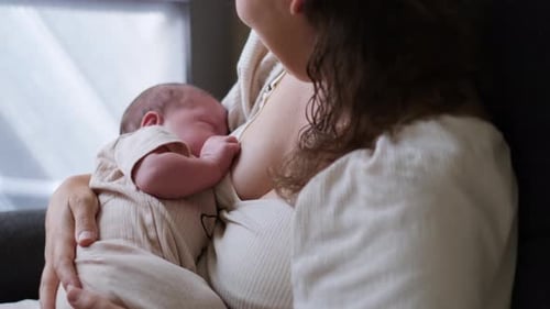Mother breastfeeding her infant in gentle indoor lighting
