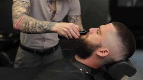 Tätowierter Friseur, der den Schnurrbart eines Kunden schneidet