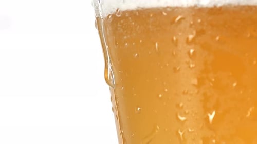 Water Drop Gliding on Cool Glass with Lager Beer Extremely Closeup Slow Motion in White Background