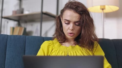 Woman Working on Laptop at Home on Sofa
