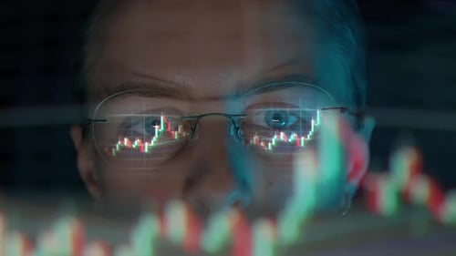 Trader usando óculos está trabalhando na tela do laptop com gráficos do mercado de ações e Bitcoin BTC