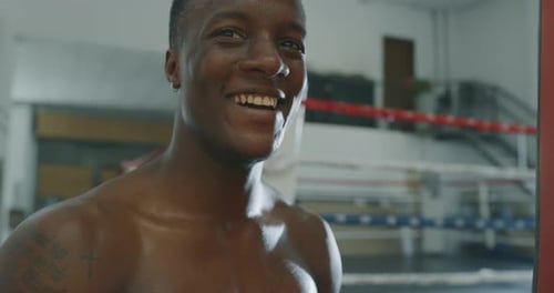 Cinematic slow motion shot of a professional young sweaty shirtless african man is smiling in came