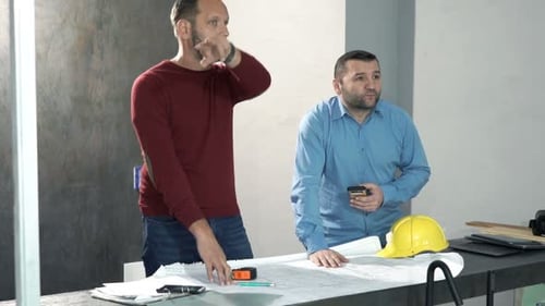 Architects reviewing blueprints in office, construction site