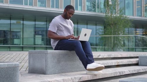 African American Man Freelancer Using Laptop Typing Chatting on Urban Street in City Guy Having