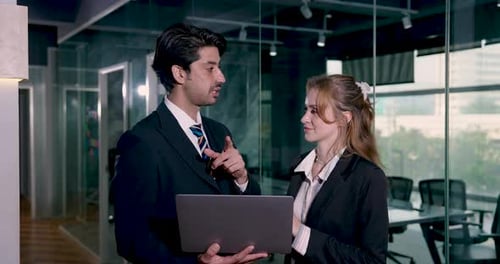 Businessman and businesswoman discussing ideas during casual standing meeting in modern office...