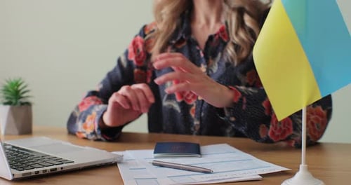 Woman Submits Passport at Desk with Ukrainian Flag