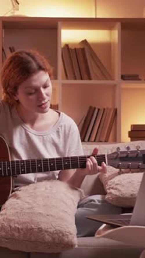 Woman Plays Guitar at Home in Cozy Lighting