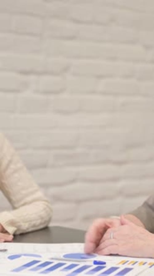 Business handshake over data graph charts on desk