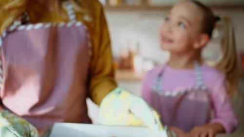 Hände haltendes Backblech mit frischen Keksen, Nahaufnahme einer blonden Familie, die Essen zubereitet