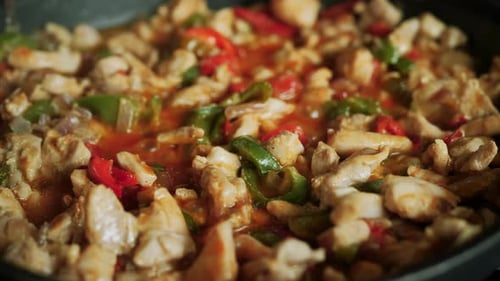 Homemade fajita mix simmering in a frying pan - bell peppers, chicken, beans, spices, onion recipe