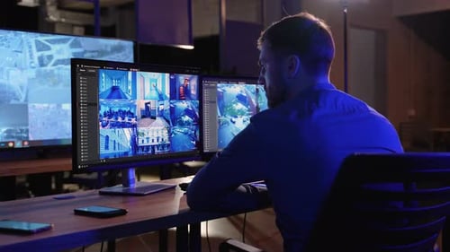 Security System Operator Looking At CCTV Camera Footage On PC