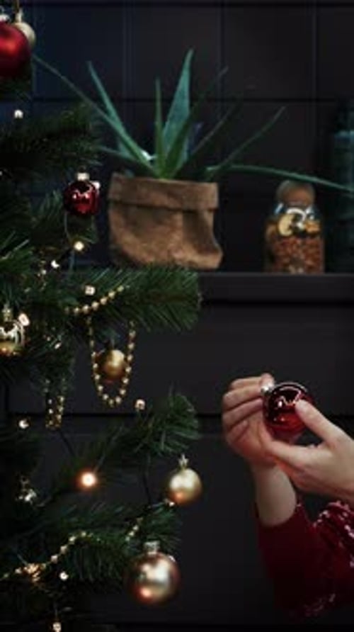 Woman Decorates Christmas Tree with Ornaments