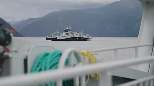 Two passenger ferries cross the Norwegian fjord passing each other. View from the ferry.