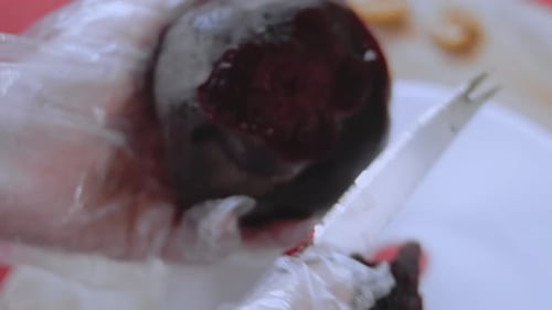 Weibliche Hände schneiden die Rote Beete mit einem Messer auf einem Küchenbrett