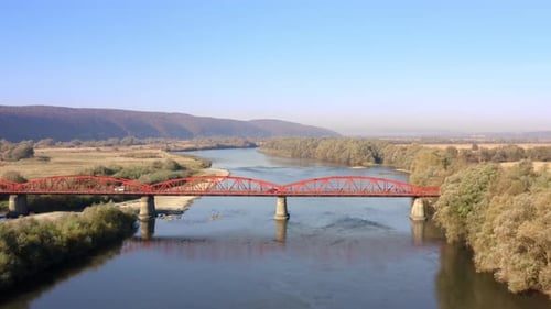 Aerial View of the Red Bridge for Vehicles Across Crystal Clear Mountain River