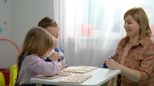 The Teacher Plays Logic Games with the Children at the Table in the Kindergarten